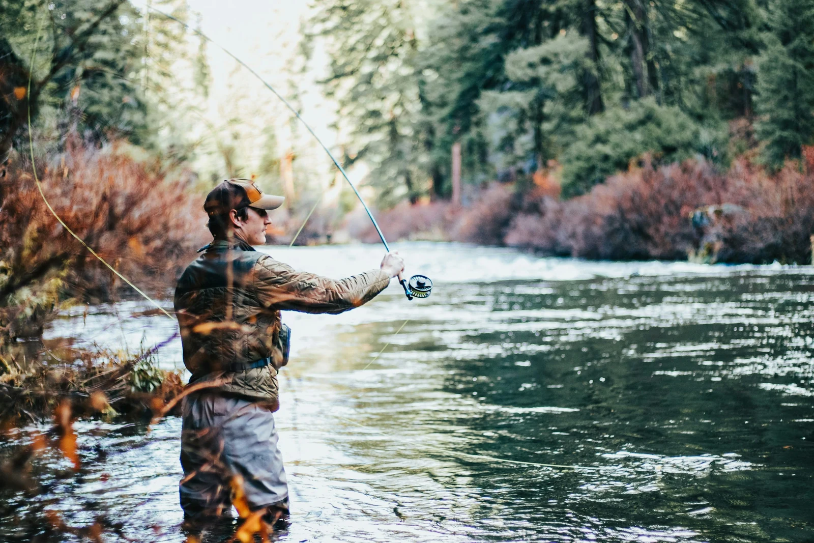 Angler casting a fly line in a forested mountain river