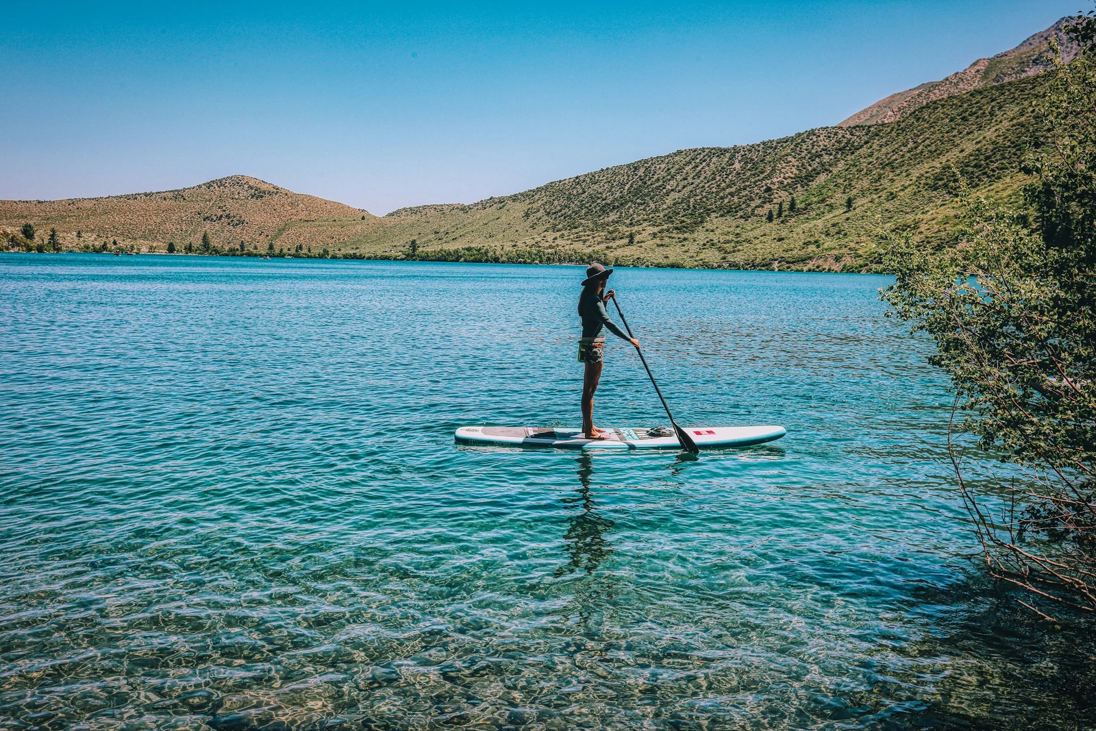 Paddleboarder crossing a clear mountain lake