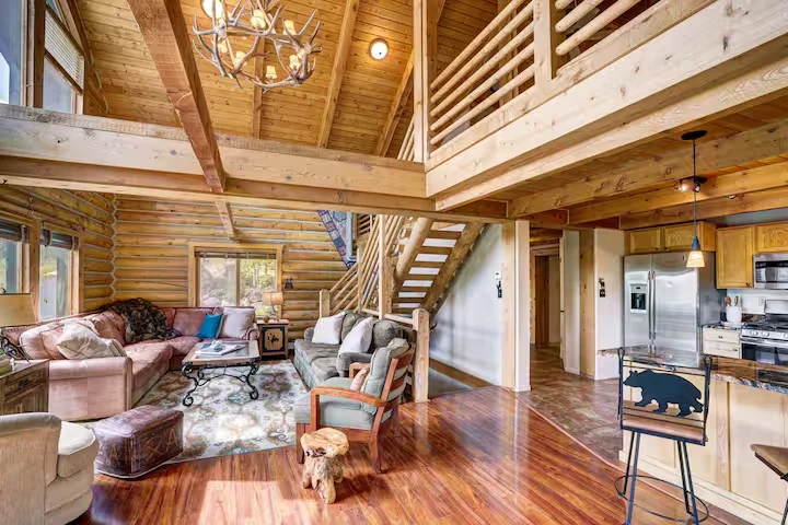 Open great room at Lincoln Lodge with exposed log beams and kitchen beyond
