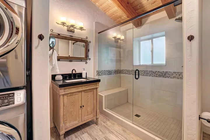 Bathroom at Lincoln Lodge with glass shower and nearby stacked laundry